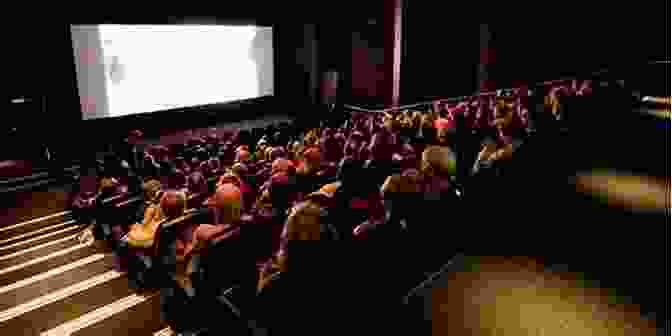 An Audience Captivated By A Nordic Film Screening In A Cozy Cinema, With The Projector Illuminating The Silver Screen. A Companion To Nordic Cinema (Wiley Blackwell Companions To National Cinemas 14)